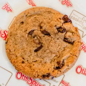 A chocolate chip cookie on Otis Spunkmeyer branded parchment paper.